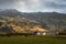 White barn with red roof in green filed surround by mountain range