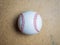 White baseball ball with red threads on a wooden surface