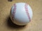 White baseball ball with red threads on a wooden surface