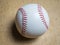 White baseball ball with red threads on a wooden surface