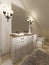 White bath sink with large mirror and sconces on the sides of th