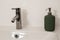 White bathroom sink with chrome faucet. Green soap dispenser