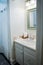 white bathroom sink with vintage tiles and rolled up organized hand towels in old cottage guest bathroom.