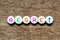 White bead with letter in word regret on wood background