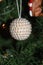 White beaded Christmas ornament hanging in tree