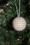 White beaded Christmas ornament hanging in tree