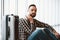 White bearded tired man sitting near suitcase