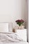 White bed with grey bedding and two pillows, white bedside table with wooden `home` sign and fresh Alstroemeria flowers