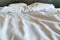White bedding set consisting of a blanket and a pillow that is out of order, The light shines on the bed in the morning