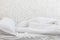 White bedding sheets and pillow in white room background. Messy bed concept in morning time