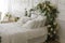 White bedroom. The bed is decorated with green leaves and flowers. Bed of newlyweds.