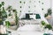 White bedroom interior with king size bed, urban jungle and green leaf on the wall