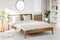 White bedroom interior with wooden king-size bed, fresh green pl