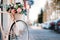 White bicycle with basket of flowers standing near the door on the street in city.