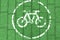 White bicycle icon on green brick background, toned