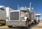 White big rig classic powerful semi truck with chrome accessories and refrigerator semi trailer standing on fuel station in Utah