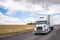 White big rig semi truck transporting food in refrigerated semi trailer moving on wide highway in California