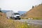 White big rig semi truck transporting goods in dry van semi trailer going on spectacular winding road between the hills with