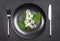 White bird cherry blooming branch on black plate with cutlery on black shale serving board. Season allergy concept.