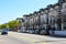 A white and black apartment building with parked cars on the street in front with lush green trees and blue sky in Atlanta