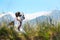 White and black fuzzy dog in grass and high mountains at background