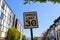 A white and black `Speed Limit 30` sign surrounded by lush green trees, apartment buildings and blue sky in downtown Atlanta