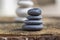 White black stone cairns, poise light pebbles on wood stump in front of brown natural background, zen like, harmony and balance