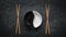White and black yin yan bowls and chopsticks on grunge background with copy space