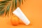 White blank cosmetic bottle, tube of cream, lotion for body, face or hand, orange fruit and branch of palm. Concept cosmetics with