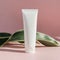 White blank cream tube and green leaves. Package mock up for beauty product