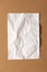 White blank crumpled paper sheet on cardboard background. Top view, vertical. Template for poster