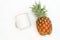 A white blank enamel mug laying out on a white table with a whole pineapple close it it