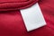 White blank laundry care clothes label on red polyester sport shirt background