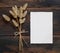 White blank paper card on wooden table with dried flowers