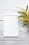 White blank photo frame with a bouquet of mimosa on a white wooden table. Minimalistic, mockup.