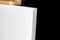 White blank synthetic canvas stands on a wooden artistic easel on black curtain background. Horizontal rectangular mockup canvas