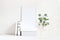 White blank wooden frame mockup with a green eucalyptus branches in glass bottle and pile of books lying on the table