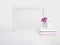 White blank wooden frame mockup with a rose flower in a porcelain cup and pile of books lying on the table. Poster