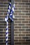 White and blue caution tape tied to a n iron post against a brick wall