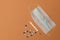 White and blue pills, mercury thermometer, face mask, brown background. Top view