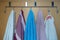 White, blue, pink towels hanging from metal hooks attached to the bathroom door. The situation in the bathroom or toilet
