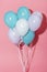 White, blue and purple decorative festive balloons with shadow on pink background.