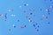 White, blue and red baloons flying high in clear blue sky