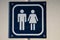 White and blue sign for toilet used by both males and females