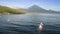 White boats with colorful bright sails floating on ocean water near seashore with huge volcano in summer. Idyllic aerial