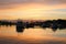 White boats and yachts moored to the pier, reflected in the water of lake Vesijarvi at sunset. Lahti. Finland