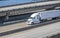 White bonnet big rig semi truck tractor transporting cargo in refrigerated semi trailer running on the multilevel overpass road