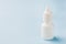 White bottle on a blue background. Round white plastic bottle for medical or cosmetic liquid, eye drops, oil. Side view