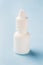 White bottle on a blue background. Round white plastic bottle for medical or cosmetic liquid, eye drops, oil. Side view