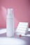 White bottle with dispenser mockup on pink backdrop in harsh light, no brand template. Cleansing facial foam container with decor